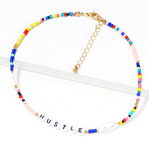 colorful necklace with alphabet beads depicting word hustle playful necklace with gold closure and pearl
